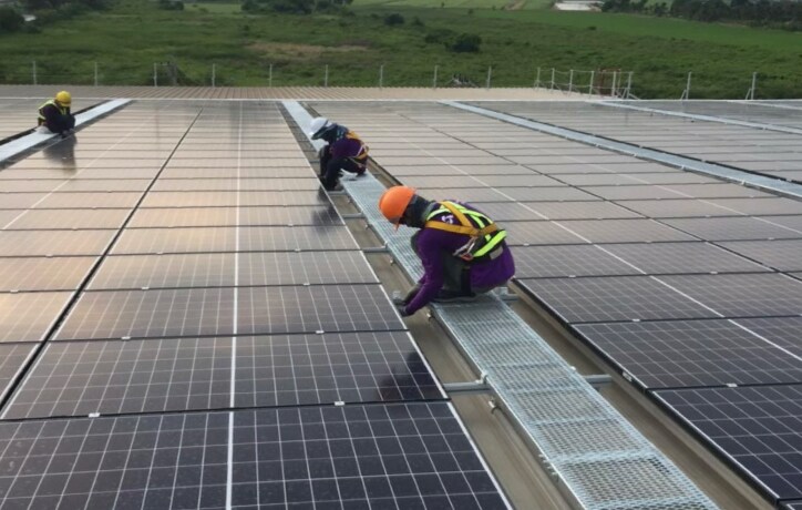 three people installing solar panels on a roof